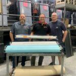 WestRock Plant saves $100,000+ in first year by going green (L. to R.) Bill Elting, Walter Cano and Westrock first pressman Frankie Sharpe showcase Prepac® Pre-impregnated wet cloth rolls at Westrock’s flat rock, NC facility. Photo - Baldwin